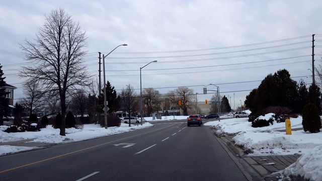 在城市灯光十字路口，汽车在繁忙的街道上行驶。在城市道路上行驶的车辆与移动的交通和雪。视频素材