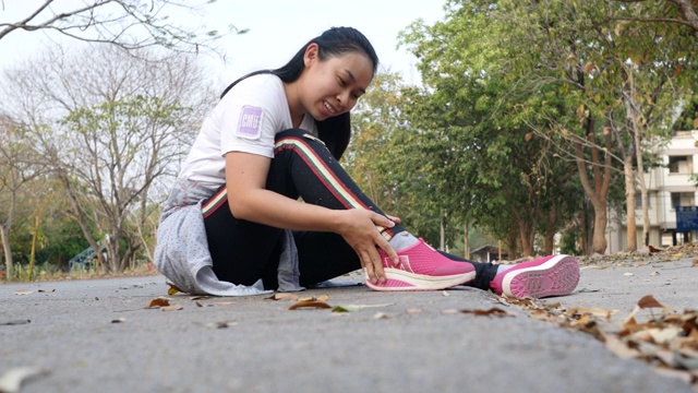 女运动员在公园跑步训练时碰到了疼痛的脚踝扭伤。女性在运动后脚踝疼痛。视频素材