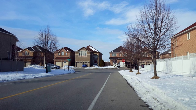 汽车在城市停车标志交叉口的街道上行驶在冬季住宅区。在城市道路上行驶的车辆与移动的交通和雪。视频素材