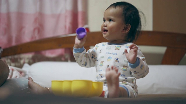 亚洲女婴笑着，在床上玩塑料积木视频素材