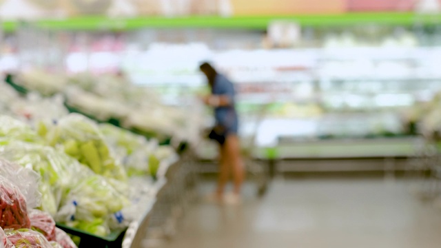 模糊背景组的人购买新鲜的食品从超市货架视频素材