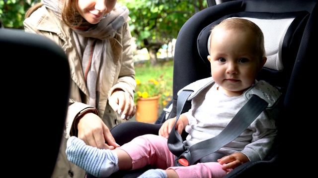 妈妈把婴儿放在婴儿座椅上，系好安全带视频素材