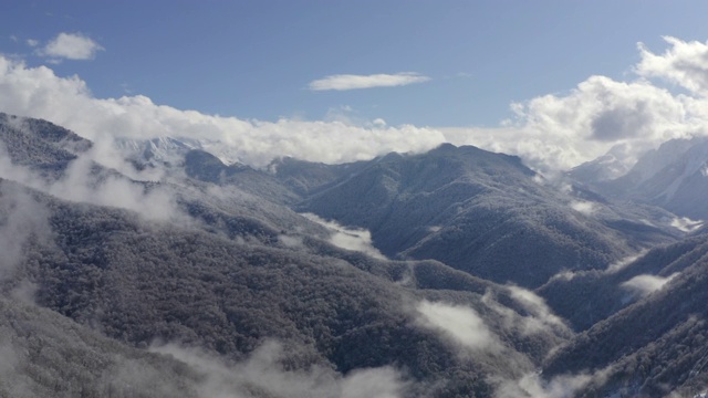 空中景观云雾笼罩美丽的山谷在蓝天的背景。在云雾中鸟瞰美丽的山景。无人机在云层中飞越冬季高地视频素材