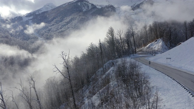 无人机拍摄越野车在冬季山区蜿蜒的道路上行驶。冬季弯弯曲曲的道路上有雪山山顶和森林空中景观。多云的山地景观从上面。在灯笼旁边视频素材