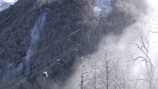 滑雪电梯在低地的雪山森林上移动。无人机视野滑雪升降机运送滑雪者和滑雪板滑雪者雪坡上的山区度假村在冬季自然景观视频素材