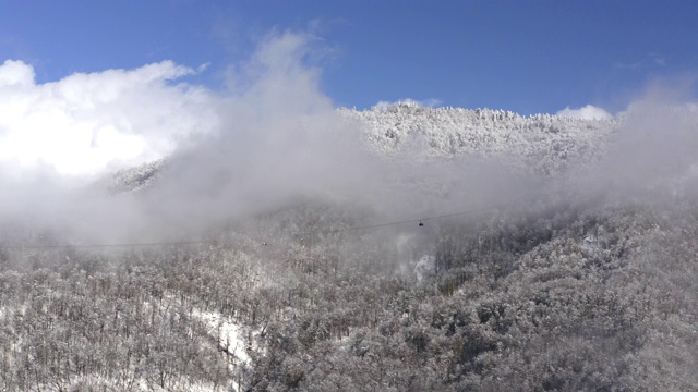 令人惊叹的鸟瞰图从无人机滑雪升降机通过云在冬季度假村。滑雪场缆车上的滑雪电梯。无人机观看雾白色的山在蓝天景观视频素材