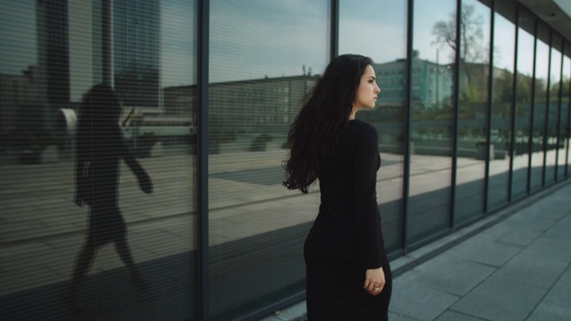 后视图女企业家触摸头发。穿着礼服走在街上的女人视频素材