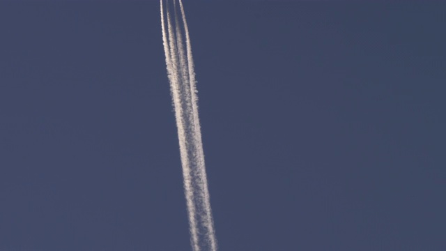 一架垂直飞行的飞机在淡蓝色天空的映衬下留下四条厚厚的白色尾迹视频素材