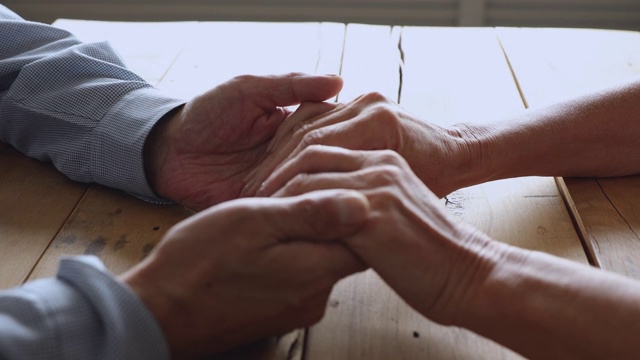 成熟的退休家庭夫妇手牵着手在桌子上。视频素材