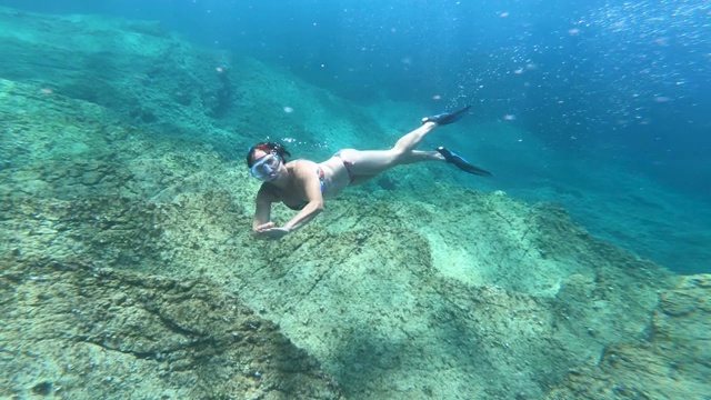 水下的观点，女孩在比基尼潜水在水晶清澈的海水视频素材