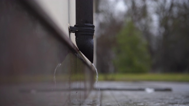 雨水从雨水排水管在建筑物墙壁上流动的特写。视频素材