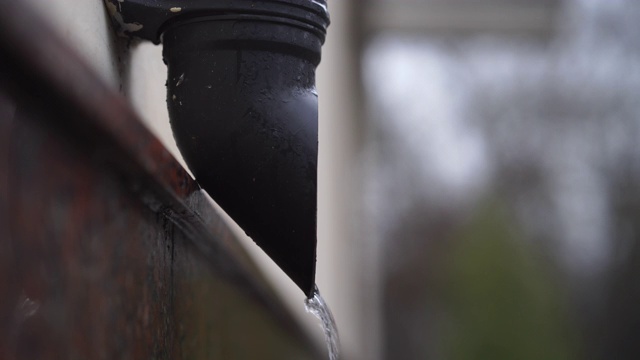 雨水从雨水排水管在建筑物墙壁上流动的特写。视频素材