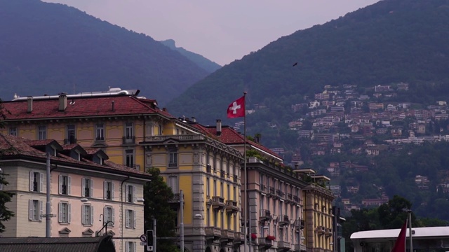 瑞士国旗。卢加诺湖建筑和蒙特布里山。视频素材