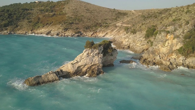 鸟瞰图的小海滩与绿松石水旁边的岩石和树木在Agia Paraskevi Halkidiki地区，希腊。从无人机视频素材