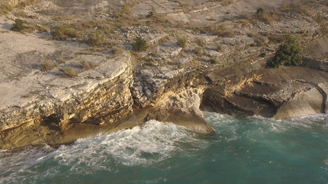 鸟瞰图的小海滩与绿松石水旁边的岩石和树木在Agia Paraskevi Halkidiki地区，希腊。从无人机视频素材