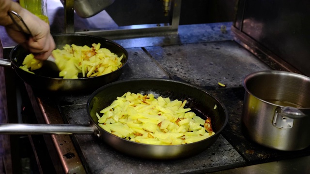 在餐厅厨房积极工作的厨师在煎锅里炸土豆视频素材