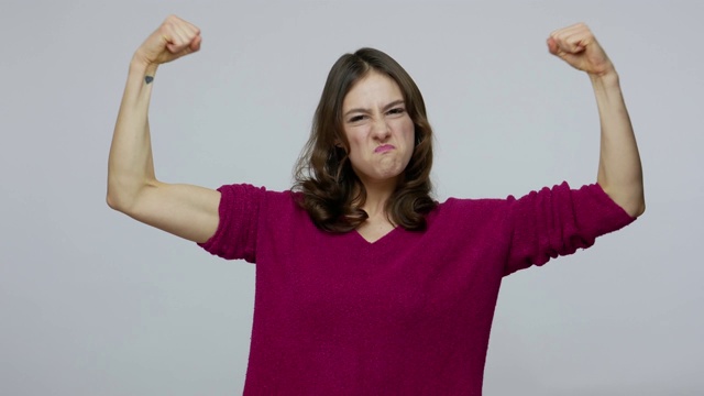 我是坚强独立的女人!自信傲慢的黑发女孩显示二头肌，指向肌肉视频素材