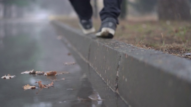 秋雨过后的落巷水坑，人们的脚踩在人行道上视频素材