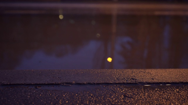 秋季多雨的夜晚城市街道，潮湿的人行道和城市交通道路被淹没视频素材