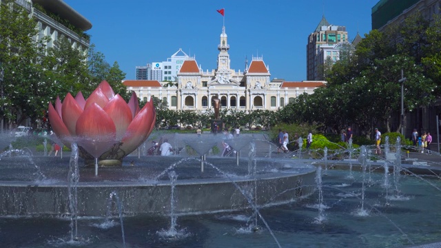 越南，胡志明市:在阳光明媚的日子里，胡志明市市政厅或胡志明市人民委员会的顶上飘扬着越南国旗。视频素材