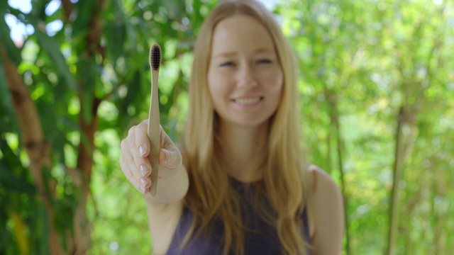 一位年轻女子展示了一把用竹子做成的木制牙刷。环保零废竹产品理念视频素材