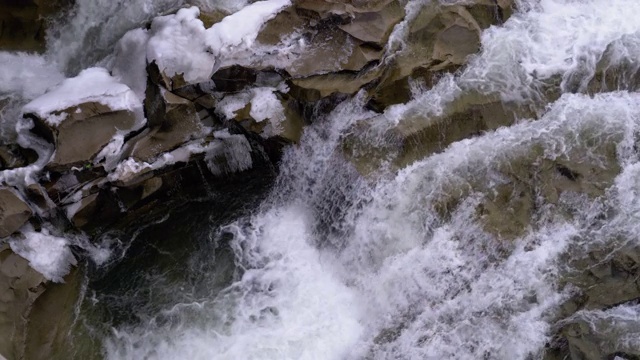 冬天的瀑布。湍急的水流从山溪和石滩与雪视频素材