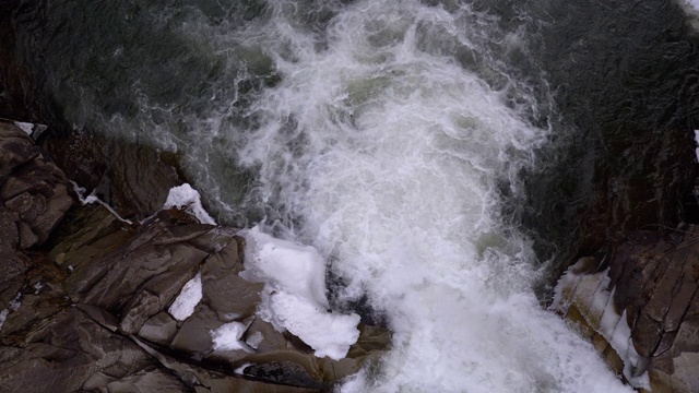 冬天的瀑布。湍急的水流从山溪和石滩与雪视频素材