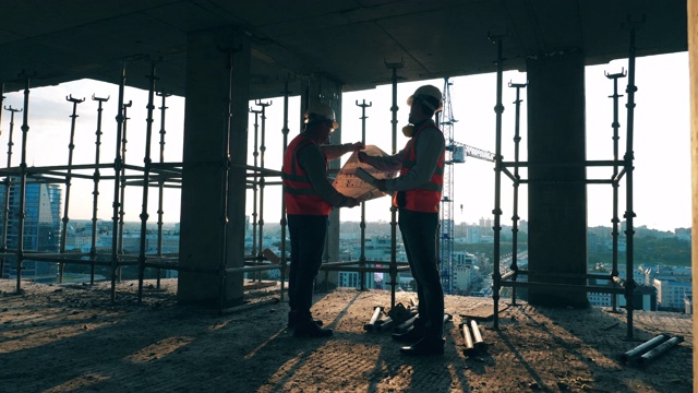 两名工程师在建筑工地上看设计图。视频素材