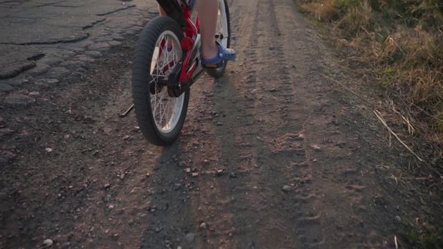 一个孩子在乡间小路上骑自行车。儿童自行车。活跃的暑假。视频素材