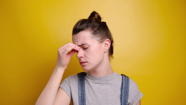 愁眉苦脸的戴眼镜的女人用揉眼睛和按摩鼻梁来释放紧张，伤心焦虑的女孩担心健康问题患上了偏头痛视频素材