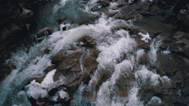 冬天的瀑布。湍急的水流从山溪和石滩与雪视频素材