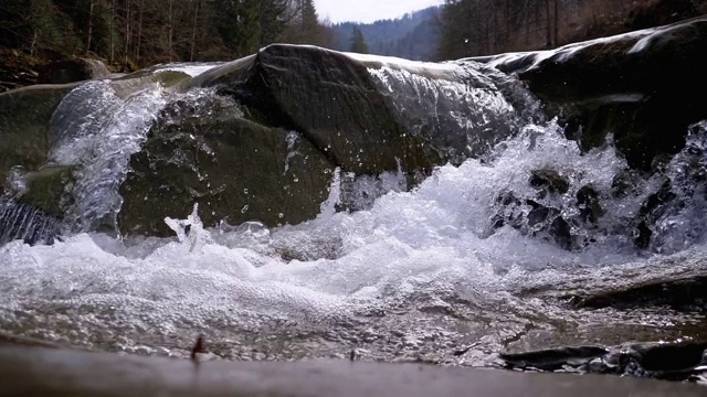 有雪的山溪和石滩。水流湍急。冬天的瀑布。慢动作视频素材