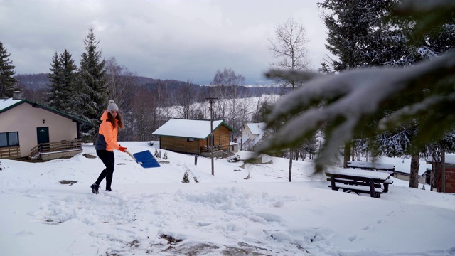 一名妇女用铁铲清理他家后院的积雪视频素材