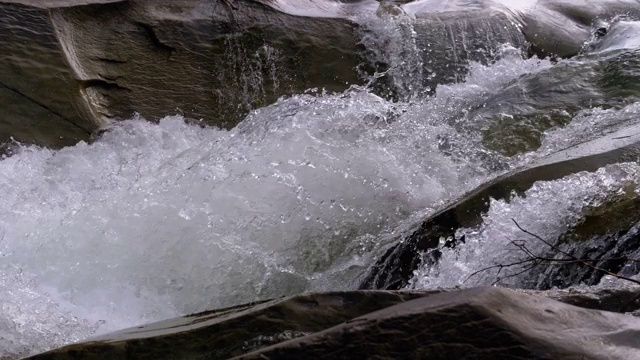 有雪的山溪和石滩。水流湍急。冬天的瀑布。慢动作视频素材