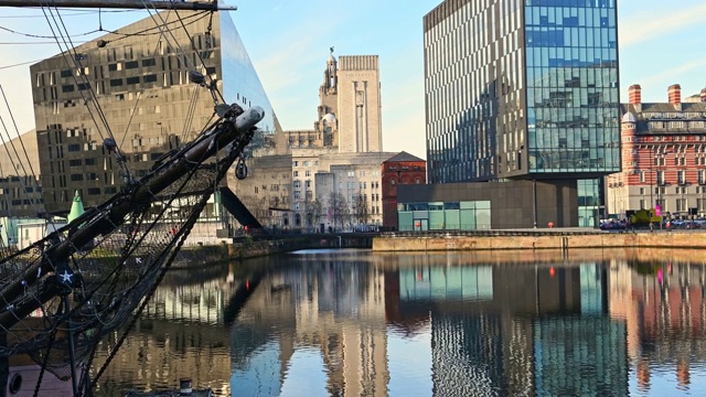 从利物浦坎宁码头(Canning Dock)重建项目周围的现代写字楼中，可以看到水中的倒影和停泊在码头边的一艘高大的船视频素材