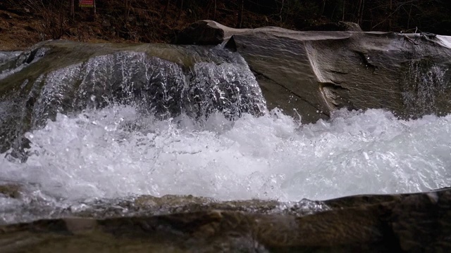 有雪的山溪和石滩。水流湍急。冬天的瀑布。慢动作视频素材