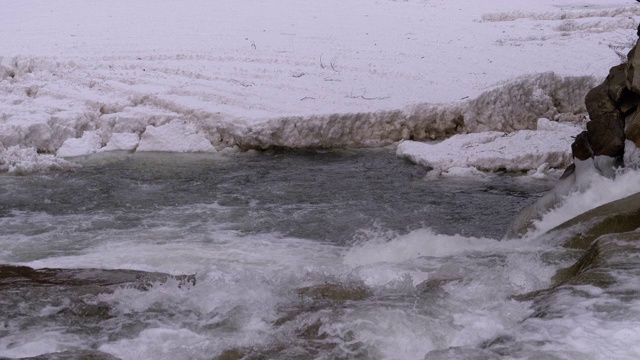 在冬天从山溪和石滩中急速流动的水和雪。瀑布。慢动作视频素材