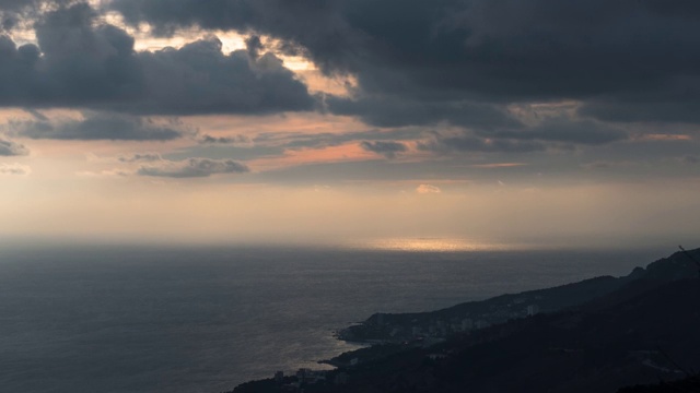 日落时，岩石海岸附近海面上的乌云和阳光，时间流逝视频素材