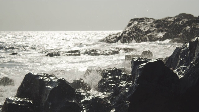 阳光下的海浪撞击着岩石视频素材