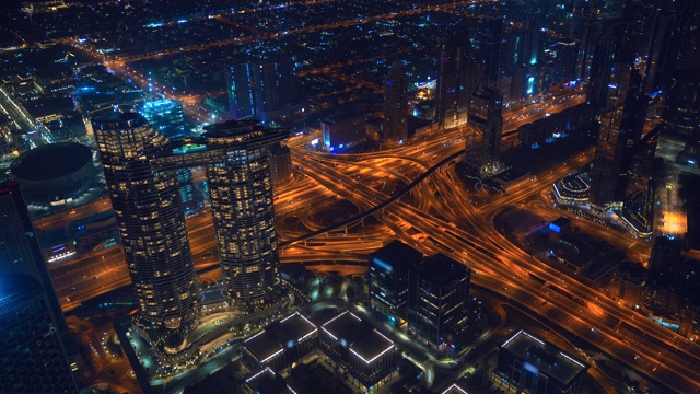 夜间阿联酋迪拜城市道路交汇处。在灯火通明的市中心，从上面俯瞰迪拜商业区的摩天大楼和现代建筑的全景视频素材