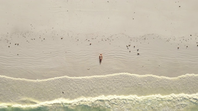 海浪拍打着躺在海滩上的比基尼女子视频素材