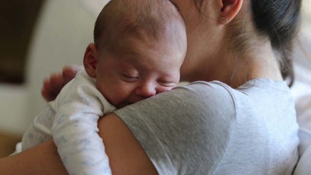 母亲抱着新生婴儿坐在家里的沙发上视频素材