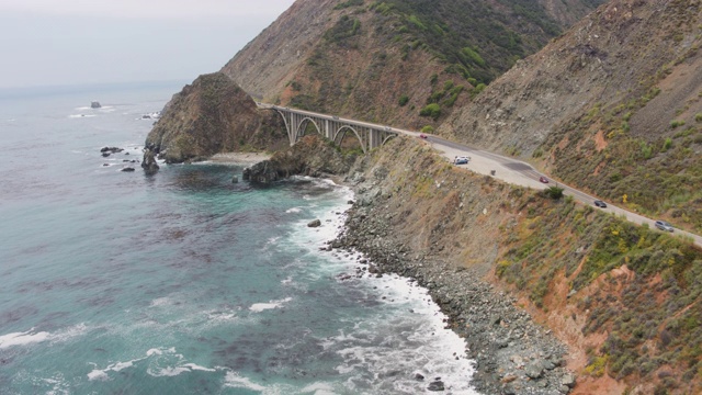 无人机拍摄的一座桥，俯瞰岩石、陡峭的海岸线公路(大苏尔，太平洋海岸公路，加利福尼亚)视频素材