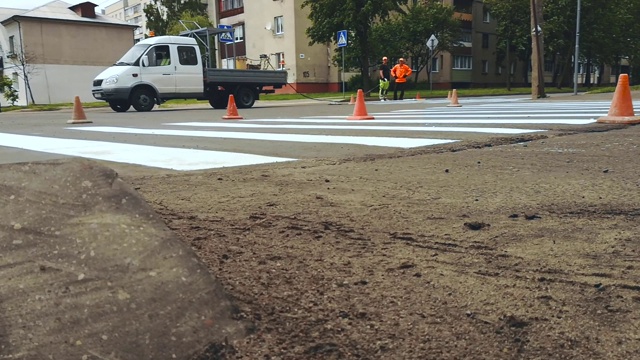 在城市街道的十字路口，工人们用油漆在人行道上画上斑马线视频素材