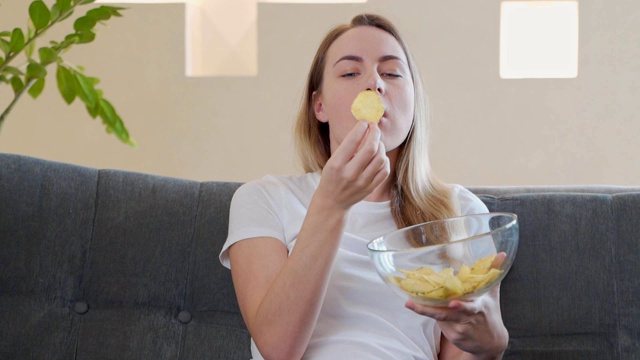 坐在沙发上吃薯片的女人视频素材