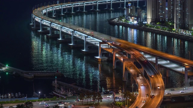 韩国釜山，光andaegyo大桥和苏永岗河/苏永古的建筑上的夜间交通视频素材