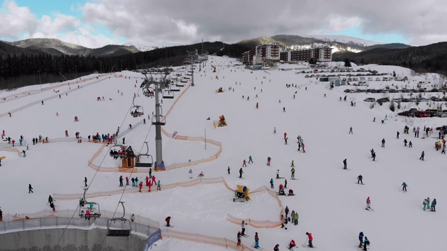 在滑雪胜地滑雪缆车附近滑雪斜坡上滑雪的许多人的鸟瞰图视频素材