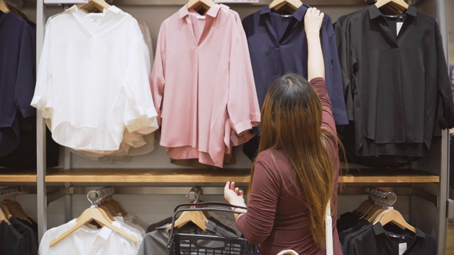 在服装店的衣架上挑选衣服的女人视频素材