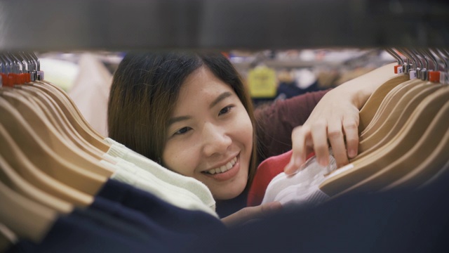 在服装店的衣架上挑选衣服的女人视频素材