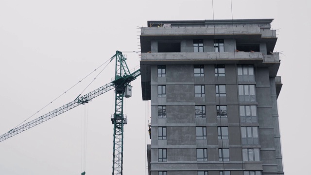 高空起重机在建筑工地施工。摩天大楼的特写，起重机正在施工中。高吊车在建筑工地施工视频素材